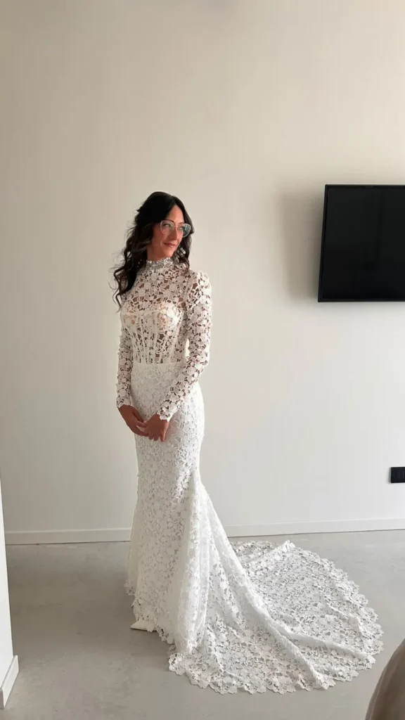 Federica in atelier con il suo abito da sposa a sirena in pizzo macramè, maniche lunghe e strascico