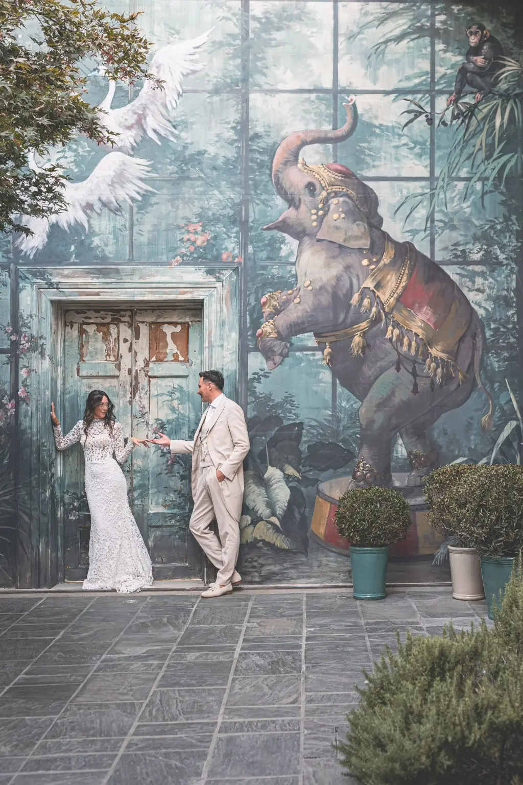 Sposa in abito a sirena in pizzo con maniche lunghe e collo alto insieme allo sposo, abiti scelti da Atelier Madà